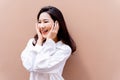 20s young Asian happy millenial woman in white shirt in clean background smiling and laughing confidently with beautiful