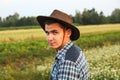 20s young man in cowboy hand on the field outside. Summer. Young farmer. Eco engineer. Organic harvest