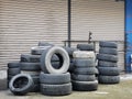 A bunch of used car rubber tyres stack together on concrete floor.