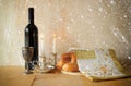 Sabbath image. challah bread and candelas on wooden table. glitter overlay