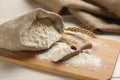 Sack and scoop of flour with wheat ears on wooden board, closeup Royalty Free Stock Photo