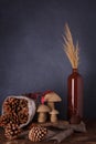 Sackcloth bag of cones, wooden mushrooms toy, vase with dry reeds, autumn composition on grey background. Vertical shot, place for