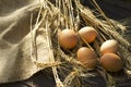 Sackcloth, wheat stems, eggs on the wooden brown background.Natural sun light