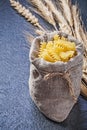 Sacking bag with raw macaroni wheat rye ears on black background Royalty Free Stock Photo