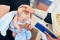 The sacrament of baptism. Newborn baby during christening and chrismation Royalty Free Stock Photo