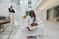 In the sacred month of Ramadan, an African American Muslim man engrossed in reading the Holy Quran is surrounded by a