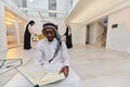 In the sacred month of Ramadan, an African American Muslim man engrossed in reading the Holy Quran is surrounded by a