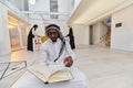 In the sacred month of Ramadan, an African American Muslim man engrossed in reading the Holy Quran is surrounded by a