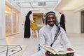 In the sacred month of Ramadan, an African American Muslim man engrossed in reading the Holy Quran is surrounded by a