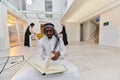 In the sacred month of Ramadan, an African American Muslim man engrossed in reading the Holy Quran is surrounded by a