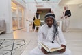 In the sacred month of Ramadan, an African American Muslim man engrossed in reading the Holy Quran is surrounded by a