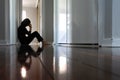 Sad woman sitting on dark home corridor floor Royalty Free Stock Photo