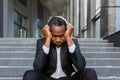 Sad african american businessman sitting on stairs outside office building, man in business suit bankrupt fired from job Royalty Free Stock Photo