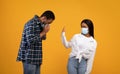 Sad african american lady in protective mask shows stop sign to man, guy sneezes and has first symptoms of disease