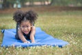 Sad African american little girl while practicing yoga on the roll mat in the park outdoor Royalty Free Stock Photo