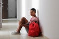 Sad African-American teenage boy sitting on floor indoors. Bullying at school Royalty Free Stock Photo