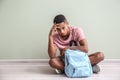 Sad African-American teenage boy sitting on floor indoors. Bullying at school Royalty Free Stock Photo