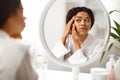 Sad african american woman looking in mirror at wrinkles around her eyes Royalty Free Stock Photo