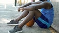 Sad Afro-American basketball player sitting on ground, lack of motivation Royalty Free Stock Photo