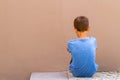 Sad alone boy sitting on the ground behind the wall outdoor Royalty Free Stock Photo