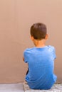 Sad alone boy sitting on the ground behind the wall outdoor Royalty Free Stock Photo