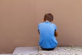 Sad alone boy sitting on the ground behind the wall outdoor Royalty Free Stock Photo