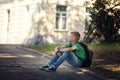 Sad alone boy sitting on road in the park outdoors Royalty Free Stock Photo