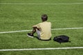 Sad alone teenage boy with backpack sitting in empty sport stadium outdoors