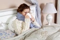 Sad alone young woman in white sweater and blue scarf feeling cold sick and resting home in bed. drinking her medicine drug and