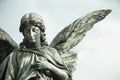 Sad angel sculpture with open long wings across the frame desaturated against a bright white sky. The sad sculpture with eyes down Royalty Free Stock Photo