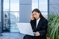 Sad and anxious Asian student, received disappointing news about entering university and college, sitting on a bench with a laptop