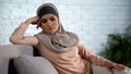 Sad arab housewife sitting on sofa at home, relations crisis, thinking trouble