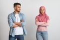 Sad arab man looking at offended muslim wife in hijab after quarrel