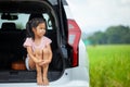 Sad asian child girl sitting alone in a car trunk and looking to the nature outside while going on vacations with their parents. Royalty Free Stock Photo