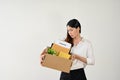 A sad Asian female office worker carrying a cardboard box with her stuff and resignation letter Royalty Free Stock Photo