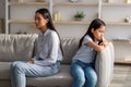 Sad asian lady mother and upset female kid daughter, having fight, quarrel, misunderstanding, sitting together on sofa Royalty Free Stock Photo