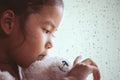 Sad asian little child girl hugging her doll and looking outside Royalty Free Stock Photo