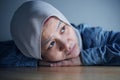 Sad Asian muslim woman laying her head down on table and looking up with blank stare thinking about something Royalty Free Stock Photo