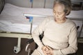 Sad asian old woman sitting in wheelchair next to hospital bed Royalty Free Stock Photo