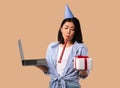 Sad Asian Woman In Hat Holding Gift Box And Laptop Royalty Free Stock Photo