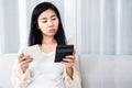 Sad Asian woman holding calculator with list of debt, expenses on notepad , female having financial problem during quarantine Royalty Free Stock Photo