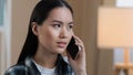 Sad asian woman millennial confused angry girl indoors talking on phone answering call worries about bad news network Royalty Free Stock Photo