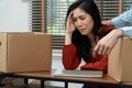 Sad Asian woman Packing belongings in a cardboard box and crying on the desk in the office After being layoff and unemployed.