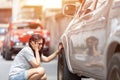 Sad asian young beautiful woman  with worried stressed face expression looking down in car wheels. Royalty Free Stock Photo