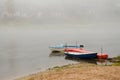 Sad autumn landscape. Fog and rain over the river. Rescue boats stand at the shore. Walk on the water in bad weather. Two boats Royalty Free Stock Photo