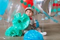 Sad baby boy celebrating first birthday. Kids birthday party decorated with balloons and colorful banner Royalty Free Stock Photo