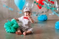 Sad baby boy celebrating first birthday. Kids birthday party decorated with balloons and colorful banner Royalty Free Stock Photo