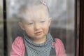 Sad baby girl staring out the window. Stay at home quarantine coronavirus pandemic prevention Royalty Free Stock Photo