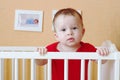Sad baby standing in white bed Royalty Free Stock Photo