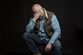 Sad bald man in jeans on a black background. Vertical. Unemployment and financial problems in the global crisis during the Royalty Free Stock Photo